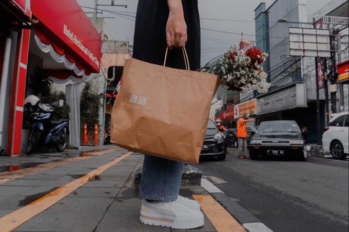 Consumidora con bolsa de papel kraft y flores (Lucky Octavia Unsplash)
